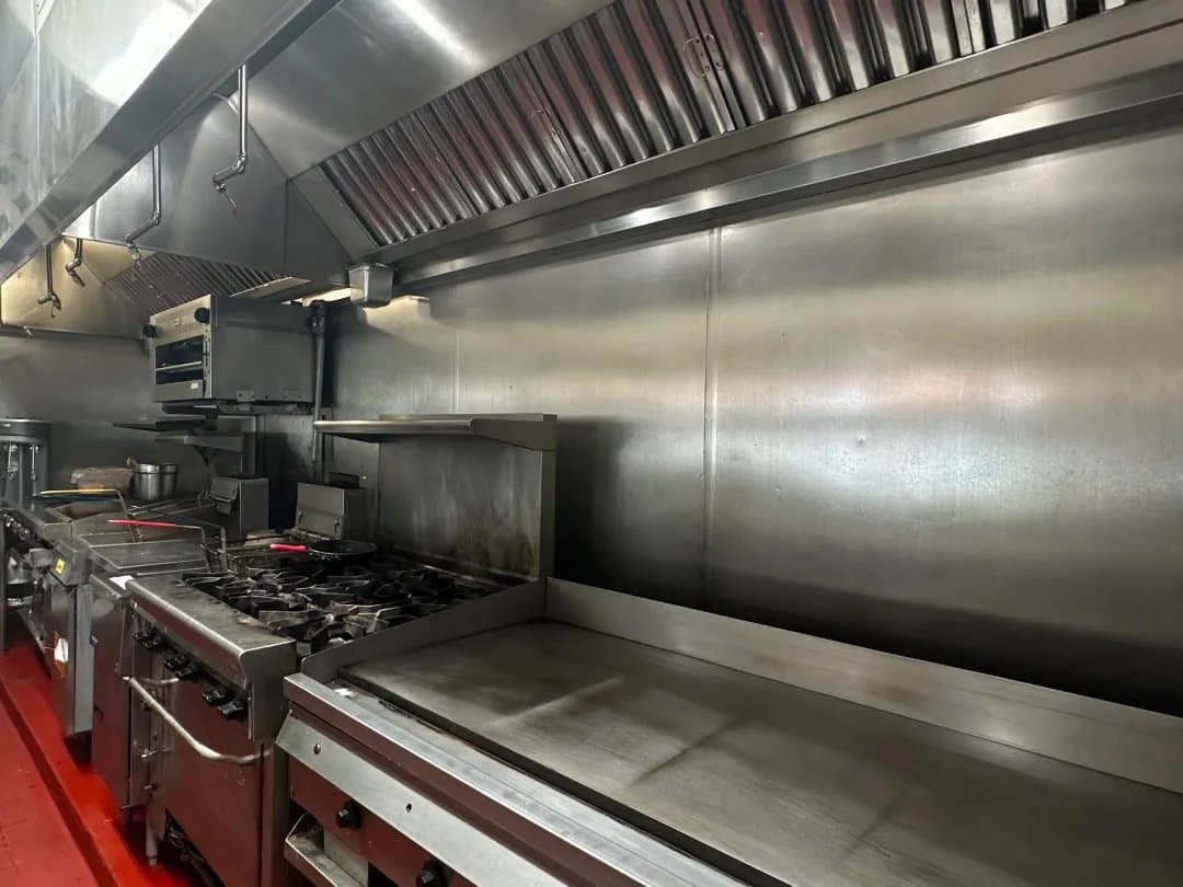 Fully equipped commercial kitchen line with hood and griddle